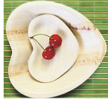 Heart shaped palm leaf plates holding two cherries